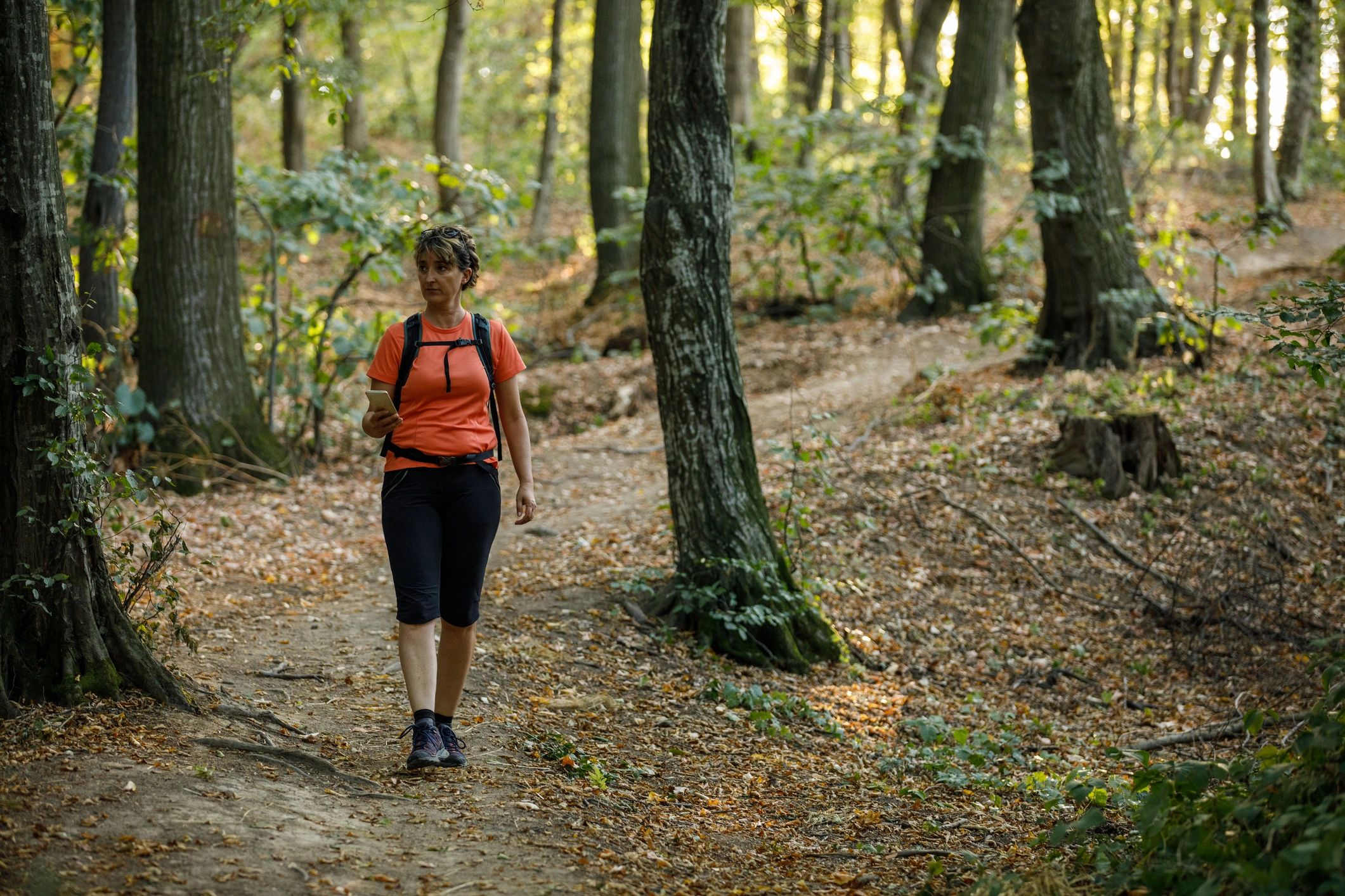 Happy mature woman taking a relaxing walk through the forest
