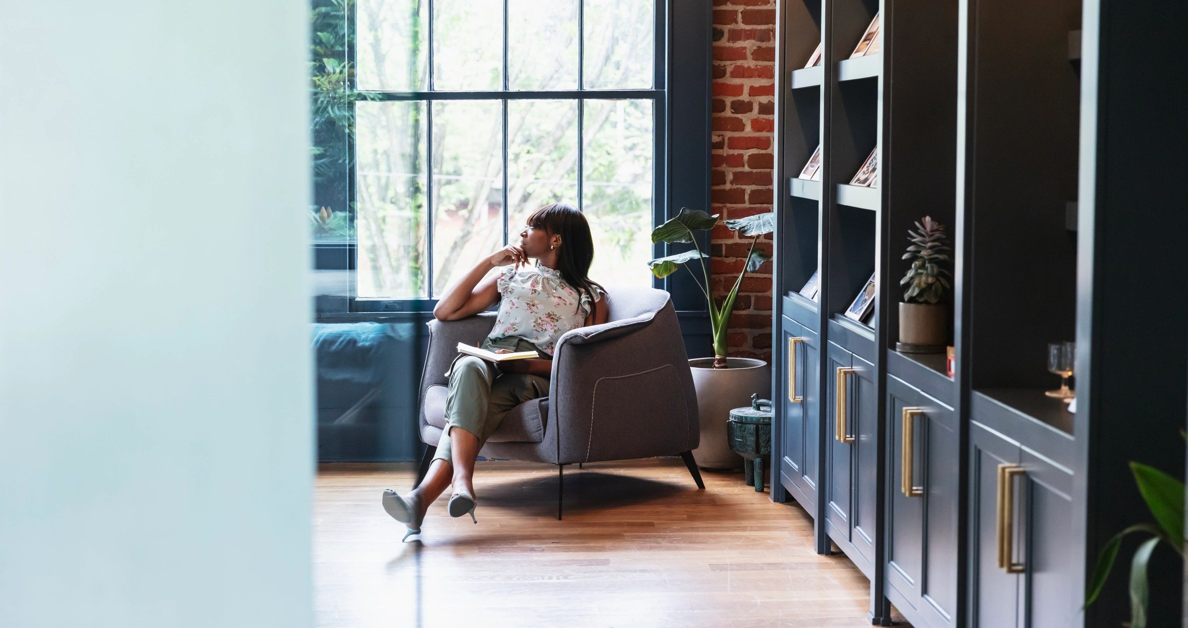 Woman sitting thoughtfully by a window in a calm setting
